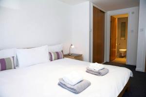 Un dormitorio con una cama blanca con toallas. en JOIVY Inviting flat with parking in Canonmills, en Edimburgo