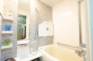 La salle de bains blanche est pourvue d'une baignoire et d'un lavabo. dans l'établissement Furano Garden House - Vacation STAY 15463, à Furano