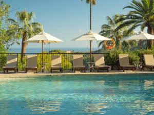 a swimming pool with chairs and umbrellas at Es Moli in Deia