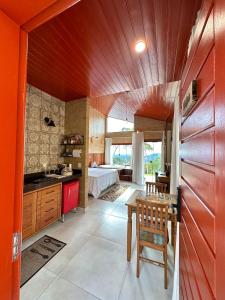 a kitchen with orange walls and a bedroom with a bed at Chales Labelle - 5 minutos do Centro e da Rodoviária de Santa Teresa in Santa Teresa