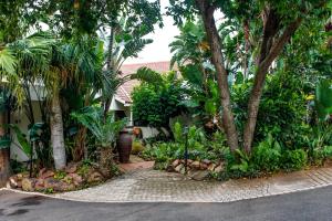 einen Garten mit Bäumen und Pflanzen auf einer Straße in der Unterkunft La Dolce Vita Umhlanga Guesthouse in Durban