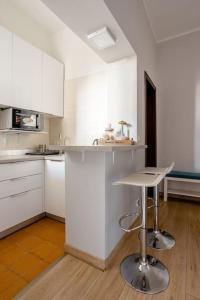 uma cozinha branca com um balcão e um banco em Centro Storico - Stazione a 500m Strategico Elegant Loft em Pádua