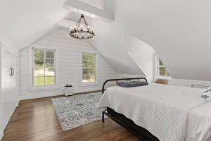 a white bedroom with a bed and a chandelier at The Wolfstead - near Mystic, Casinos & Beaches in Stonington