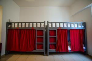ドバイにあるLunar Hostelのベッドルーム1室(赤いカーテン付きの二段ベッド2組付)
