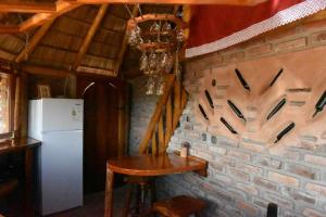 a kitchen with a brick wall with a table and a refrigerator at La Oca en el Cielo in Quebrada de los Cuervos