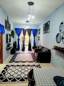 LH Alisha Homestay Bandar Utama Gua Musang في غُوا موسانغ: غرفة معيشة مع أريكة وستائر زرقاء