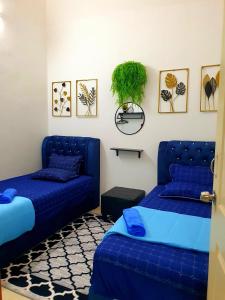 una camera con due letti e un divano blu di LH Alisha Homestay Bandar Utama Gua Musang a Gua Musang