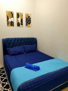 LH Alisha Homestay Bandar Utama Gua Musang في غُوا موسانغ: سرير ازرق في غرفة مع صورتين على الحائط