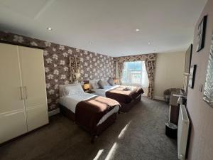 a hotel room with two beds and a window at Lauriston & Lawton Court Hotel in Llandudno