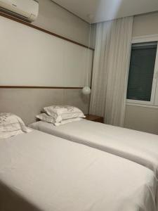 a bedroom with two white beds and a window at Praia do Santinho, de frente para mar in Florianópolis