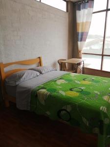 a bedroom with a bed with a green comforter at CASA VILLA SOL in Tumbes