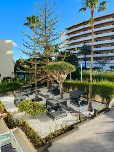 a park with benches and palm trees and a building at Apartamentos Fayna in Playa del Ingles