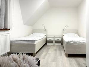 Habitación con 2 camas, paredes blancas y suelo de madera. en Apartment Nela, en Pavčina Lehota
