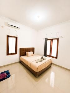 a bedroom with a bed and two windows at Homestay Kamar Tamu Godean in Godean