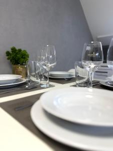 una mesa cubierta con platos blancos y copas de vino en Apartment Nela, en Pavčina Lehota