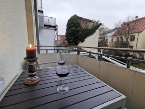 a candle and a glass of wine on a table on a balcony at Apartment "Matt Rose" Rostock in Rostock