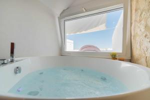 a bath tub in a bathroom with a window at Jacuzzi Amanecer de Plata Decoración Romántica in Chiclana de la Frontera