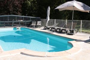 - une piscine avec 2 chaises et un parasol dans l'établissement Le Moulin Du Landion Hôtel et Spa, à Dolancourt