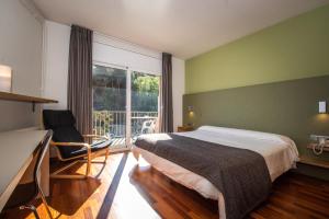 a bedroom with a bed and a desk and a window at Hotel Robert in La Pobla de Claramunt