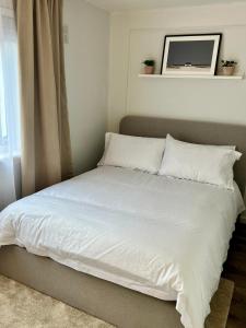 a bed with white sheets and pillows in a bedroom at House with garden and parking 15 min to City Center in Edinburgh