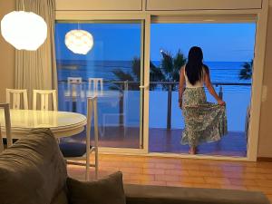 Una donna in piedi su un balcone che guarda l'oceano di Apartamento con vistas al mar y piscina a Pineda de Mar