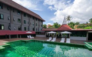 a hotel with a swimming pool in front of a building at Tuana Hotels The Phulin Resort in Karon Beach