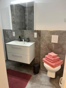 a bathroom with a sink and a toilet with towels at Ferienwohnung LINA in Bitburg