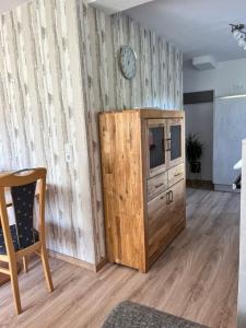 a room with a wooden cabinet and a clock on the wall at Ferienwohnung LINA in Bitburg +3 photos