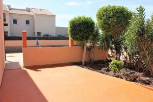 un patio con árboles y una valla amarilla en CASA MARTA duplex con piscina privada en Corralejo, en Corralejo