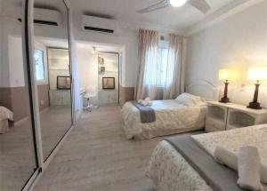 a white bedroom with two beds and a mirror at BREEZE VIEW house by the sea in Corralejo