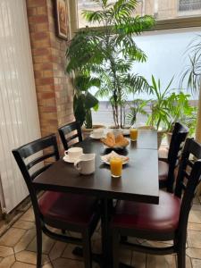 a dining room table with chairs and a table with orange juice at Hôtel Jarry Confort in Paris