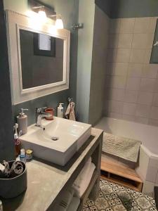 La salle de bains est pourvue d'un lavabo, d'un miroir et d'une baignoire. dans l'établissement Rez de chaussée villa avec piscine, à Piana
