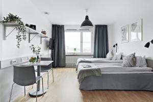 a white bedroom with two beds and a table at Forenom Aparthotel Stockholm Alvik in Stockholm