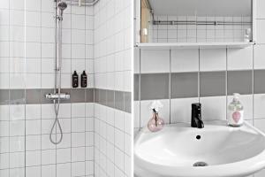 baño blanco con ducha y lavamanos en Forenom Aparthotel Stockholm Alvik en Estocolmo