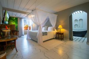 1 dormitorio con cama con dosel, mesa y comedor en Pedra da Laguna Boutique Hotel SPA, en Búzios