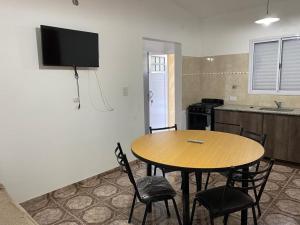 a table and chairs in a kitchen with a tv on the wall at Cabañas Emilia in Mina Clavero