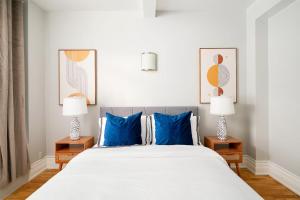a bedroom with a bed with blue pillows and two lamps at 73-208 New 2BR 2BATH UWS Doorman Gym in New York