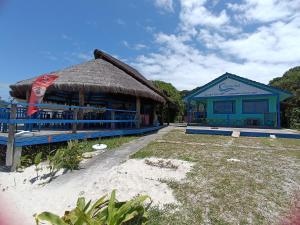 a building with a straw roof on the beach at Pousada Oceano Azul in Ilha do Mel
