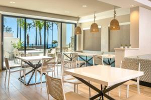 un restaurant avec des tables, des chaises et des palmiers dans l'établissement SpringHill Suites by Marriott San Diego Carlsbad, à Carlsbad