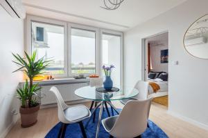 a living room with a glass table and white chairs at Bella Luna Luxury Suites - Oasis Gem Near Stadium & Old Town in Warsaw