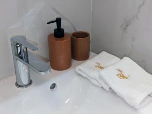 a bathroom sink with two cups and towels on it at Bella Luna Luxury Suites - Oasis Gem Near Stadium & Old Town in Warsaw +25 photos