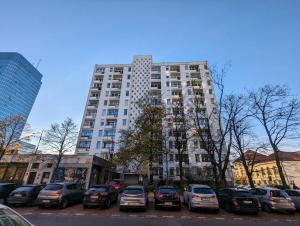 a tall building with cars parked in a parking lot at Bella Luna Luxury Suites - Oasis Gem Near Stadium & Old Town in Warsaw
