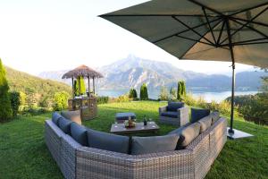 a patio with a couch and an umbrella at Naturtalente Berghaus - Mountainview Big in Innerschwand am Mondsee