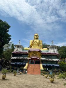 een groot gouden standbeeld voor een gebouw bij Sigiri Corridor Home Stay in Sigiriya
