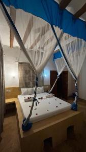 a bedroom with a canopy bed with confederacistacistacistacist at Stonefish Inn Jambiani in Jambiani