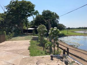 a garden with flowers and a fence next to a river at Hostel Camping Road Park Pantanal Sul in Corumbá
