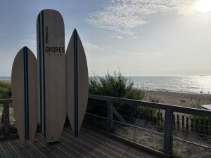 two surfboards are standing on a boardwalk with the beach at Chalet paisible à la plage, piscine et tennis in Ondres