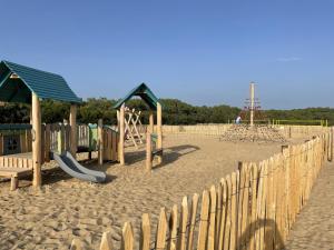 um parque infantil com equipamento de brincar na areia em Chalet paisible à la plage, piscine et tennis em Ondres