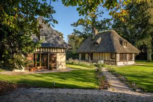 een oud huis met een rieten dak op een gazon bij Maisons Pommes in Ablon
