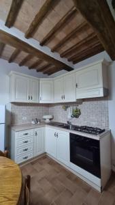 una cucina con armadietti bianchi, piano cottura e tavolo di Casa vacanze “La casetta di Anna” a Castel Viscardo